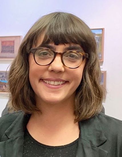Aimee Buyea in front of artworks hanging on a gallery wall
